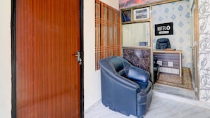A reception desk with a sign reading 'HOTEL,' a wooden door, and a blue leather chair. - Saver Doublesuper Hotel O Sudhirpur (Varanasi)
