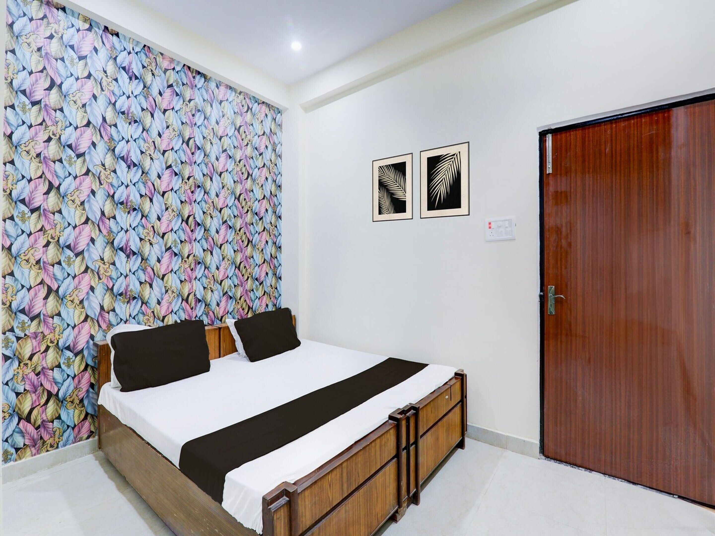 A bedroom with a bed, a wooden wardrobe, a door, and a wall with a leaf pattern.