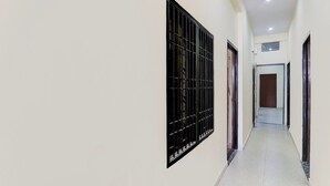A hallway with a barred window, a door at the end, and a tiled floor. - Saver Doublesuper Hotel O Sudhirpur (Varanasi)