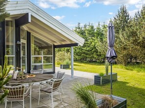 Ett modernt hus med en uteplats, utomhusmöbler och en trädgård.