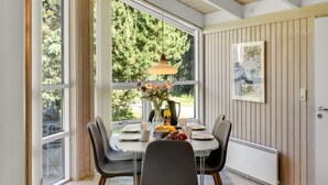 A dining area with a table set for two, large windows, a pendant light, and a radiator. - "Ilya" - 900m from the sea by Interhome (Løkken)