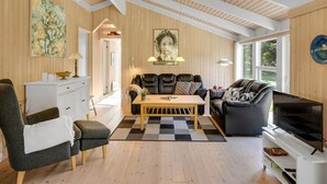 A modern living room with a high ceiling, wooden beams, a sofa, a coffee table, a TV, and a desk. - "Ilya" - 900m from the sea by Interhome (Løkken)