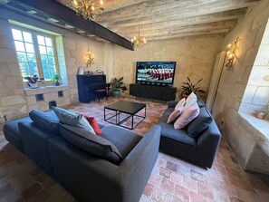 Een woonkamer met twee banken, een salontafel, een piano en een televisie.