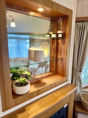 A wooden-framed mirror with a shelf below, a potted plant, and a hanging light fixture.
