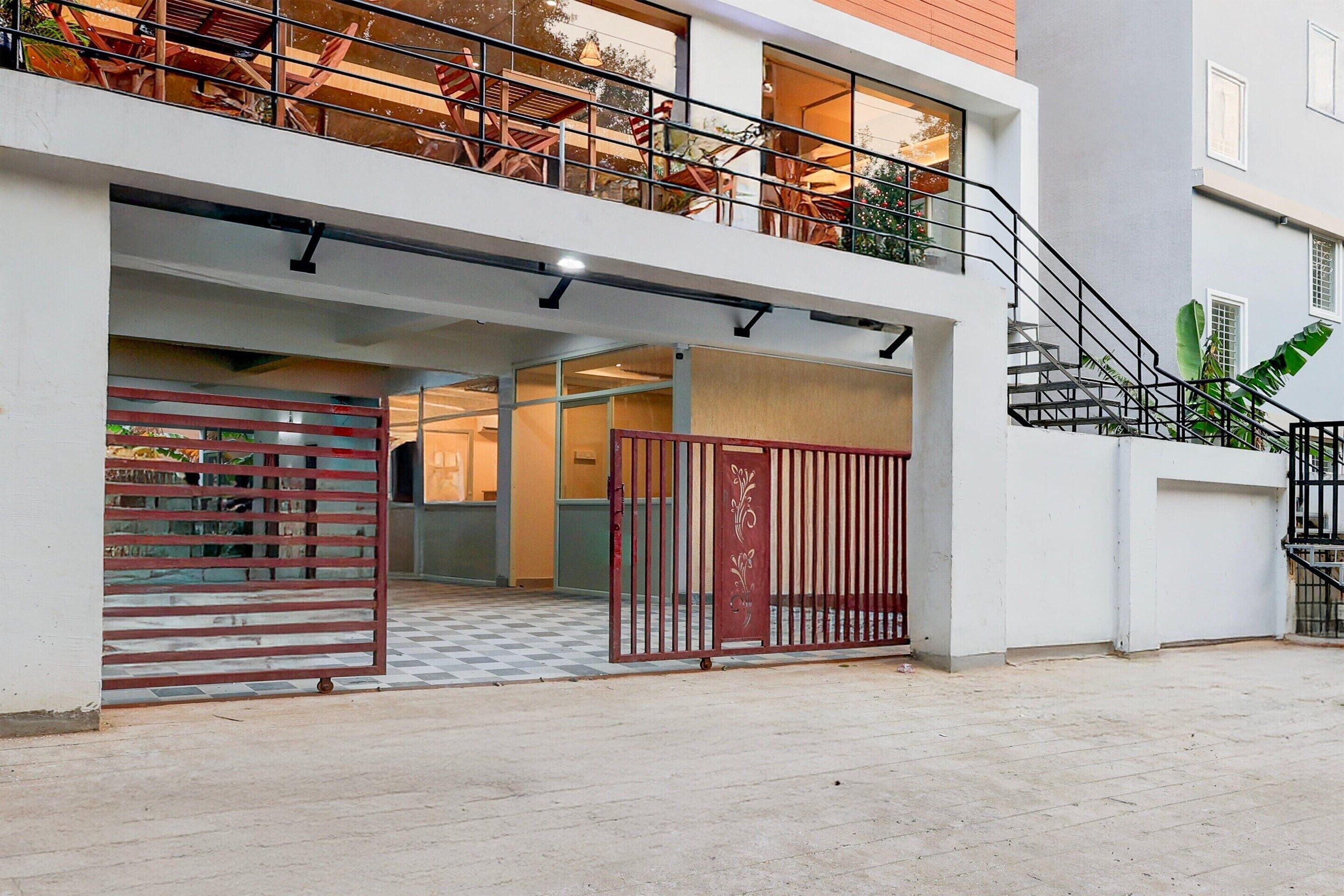 A modern building with a gated entrance, a staircase, and a balcony with outdoor furniture.