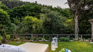 A garden setting with a bed, a table with a bottle and glass, and lanterns. - Apartment in Vorno Near Lucca City Center (Capannori)