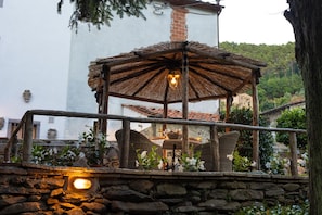 A stone wall, wicker furniture, and a thatched-roof structure with a light fixture. - Apartment in Vorno Near Lucca City Center (Capannori)
