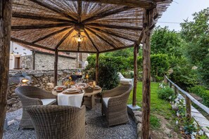 An outdoor dining area with wicker furniture, a round table, and a thatched roof structure. - Apartment in Vorno Near Lucca City Center (Capannori)