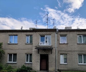A multi-story residential building with a brick facade, multiple windows, and satellite dishes on the roof. - Newly renovated 1 bedroom, nice and bright apartment with fast WIFI and parking (Jelgava)