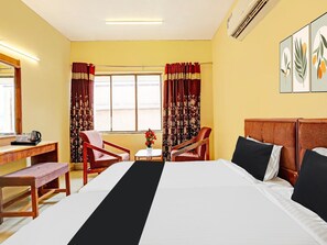 A hotel room with a bed, two chairs, a small table, a desk with a kettle, and a window with curtains. - Hotel O Gajuwaka Near Kurmanpalem (Visakhapatnam)