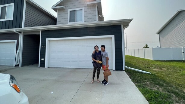 A residential building with a garage, a driveway, and a well-maintained lawn.