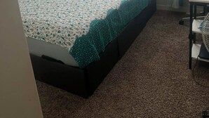 A bedroom with a bed, a desk, and a window.
