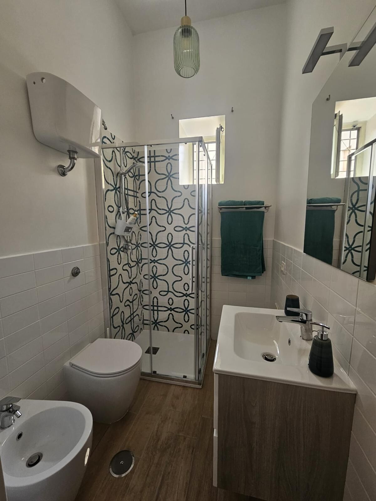 Een badkamer met douche, toilet, wastafel en spiegel.
