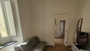 Un soggiorno con un divano, un mobile TV e una porta che dà su un'altra stanza.
