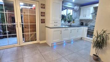 A spacious kitchen with white cabinets, a large window, and a sliding glass door leading to an outdoor area.