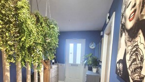 A hallway with a hanging plant, a white door, and a wall with a mural. - 3BR Tropical Escape in Lisburn and Castlereagh (Lisburn)