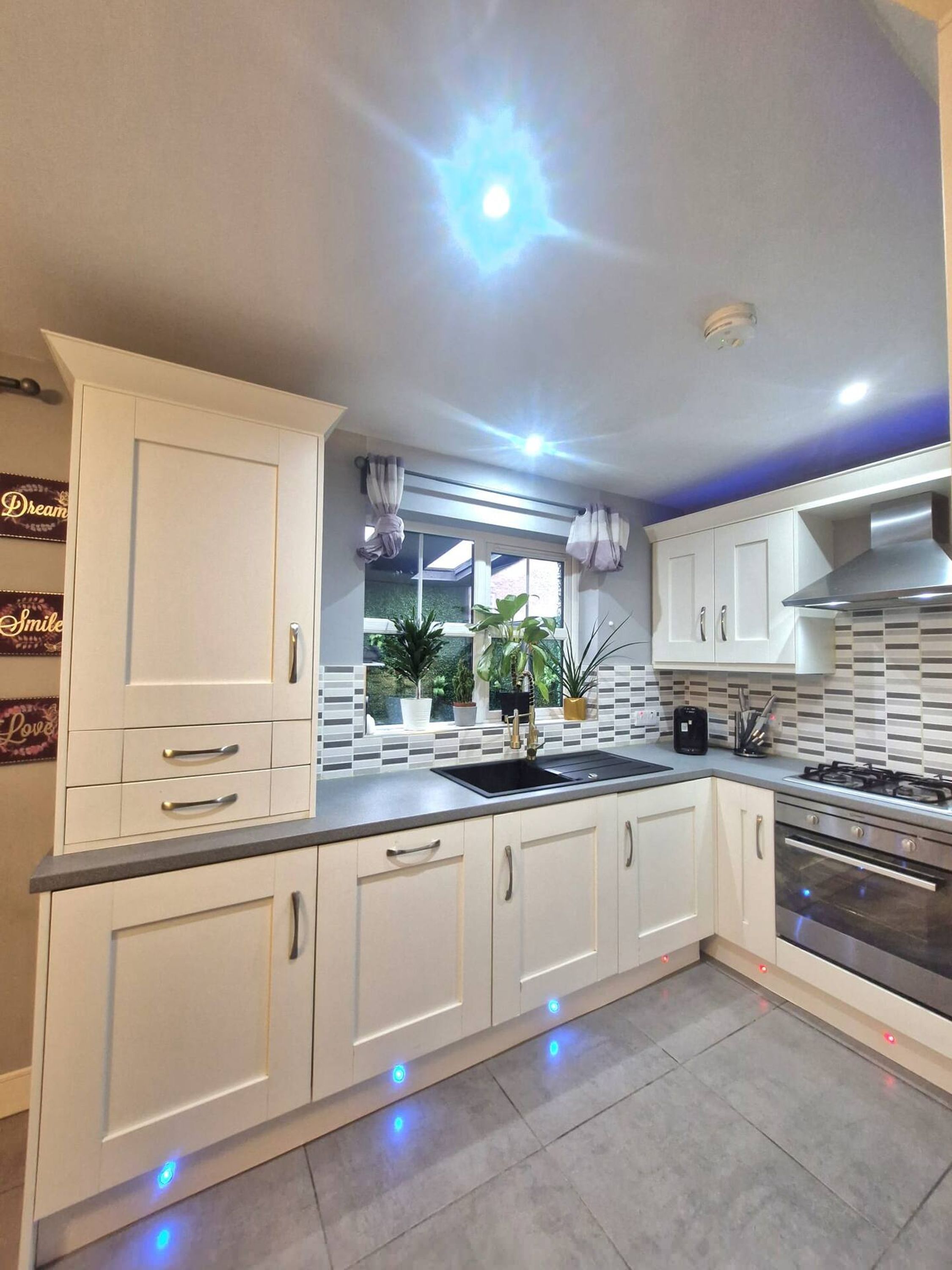 A modern kitchen with white cabinetry, a black countertop, and a stainless steel stove.