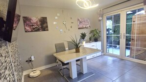A modern dining area with a table, chairs, and a ceiling light fixture. - 3BR Tropical Escape in Lisburn and Castlereagh (Lisburn)