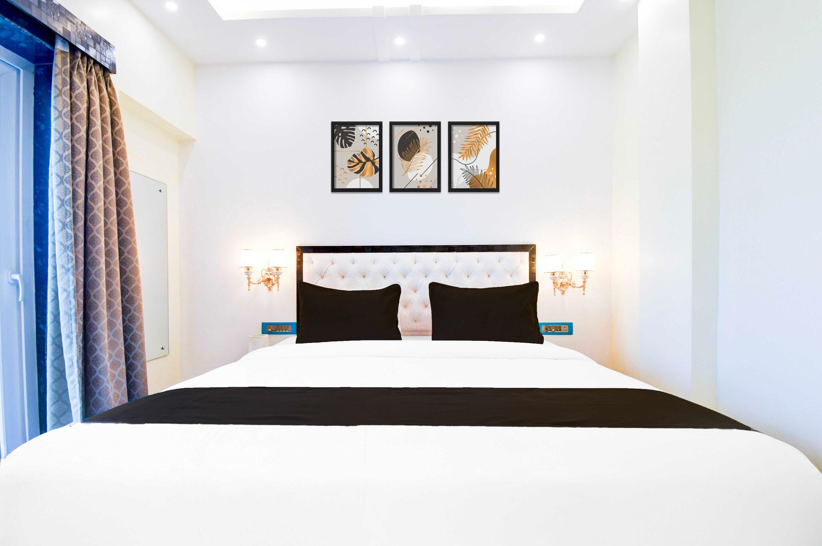 A hotel room with a large bed, a tufted headboard, wall-mounted artwork, and bedside lamps.