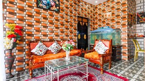 Uma sala de estar com parede estampada, um conjunto de sofá, uma mesa de centro de vidro e uma televisão.