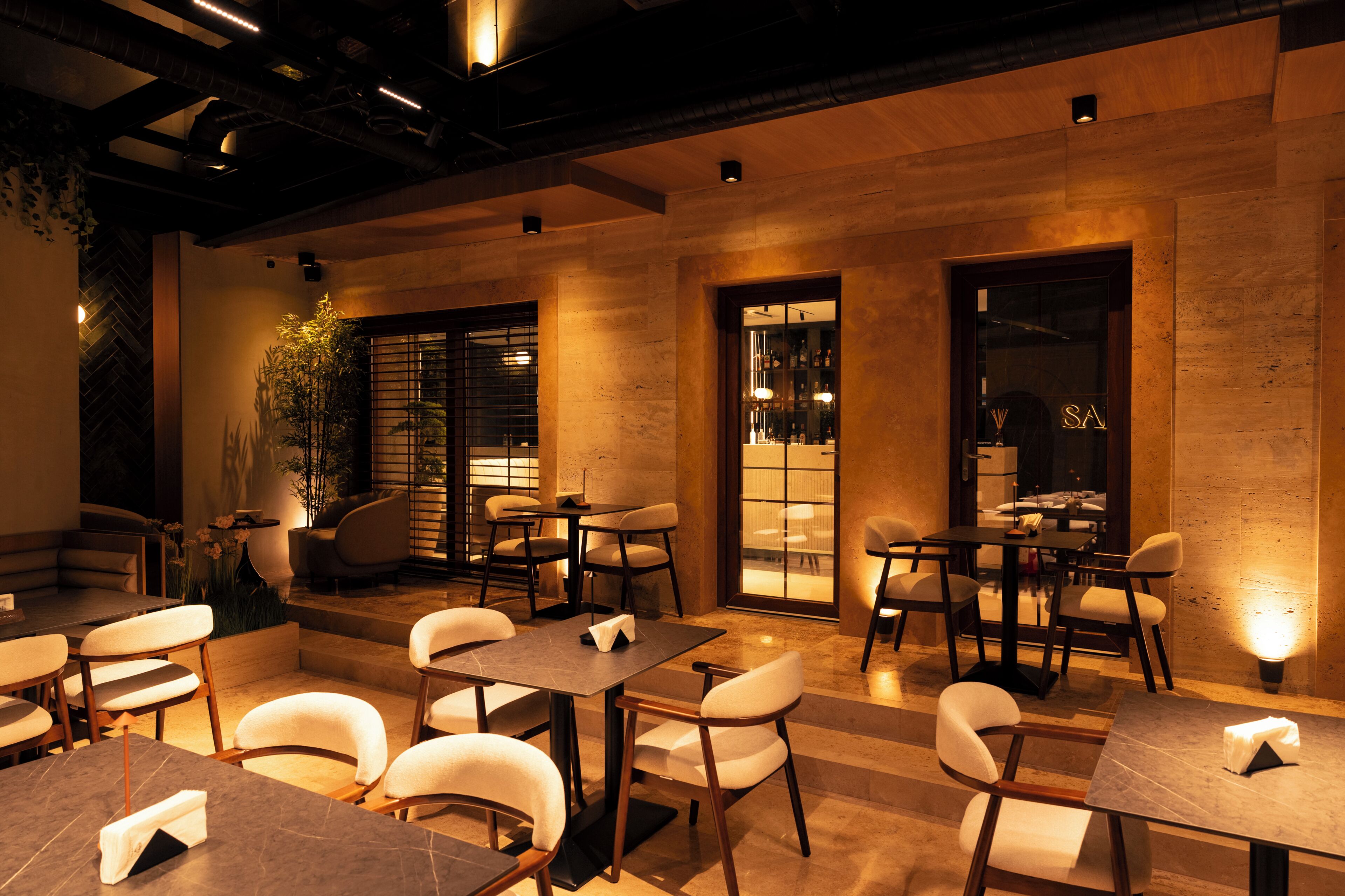 A restaurant with tables and chairs, a bar area, and a staircase leading to an upper level.