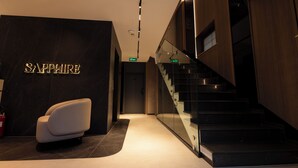 A modern interior with a marble wall, a sofa, and a staircase.