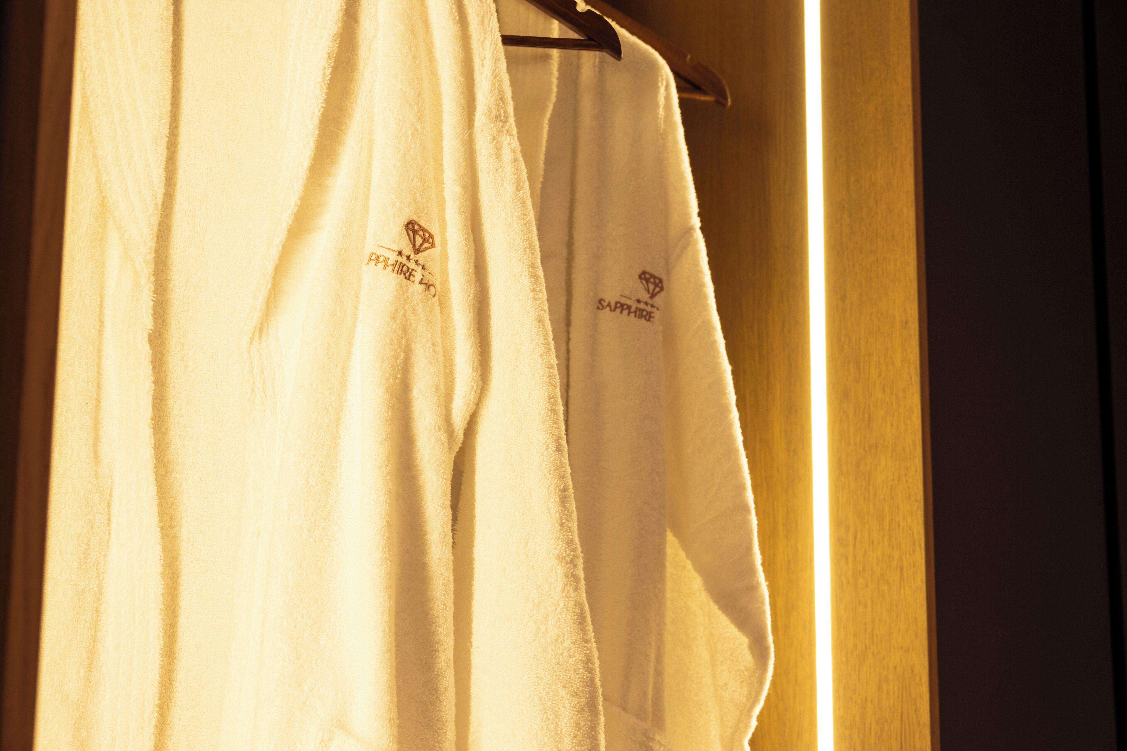 A white towel with 'SAPPHIRE HO' embroidered on it hanging on a wooden rack.
