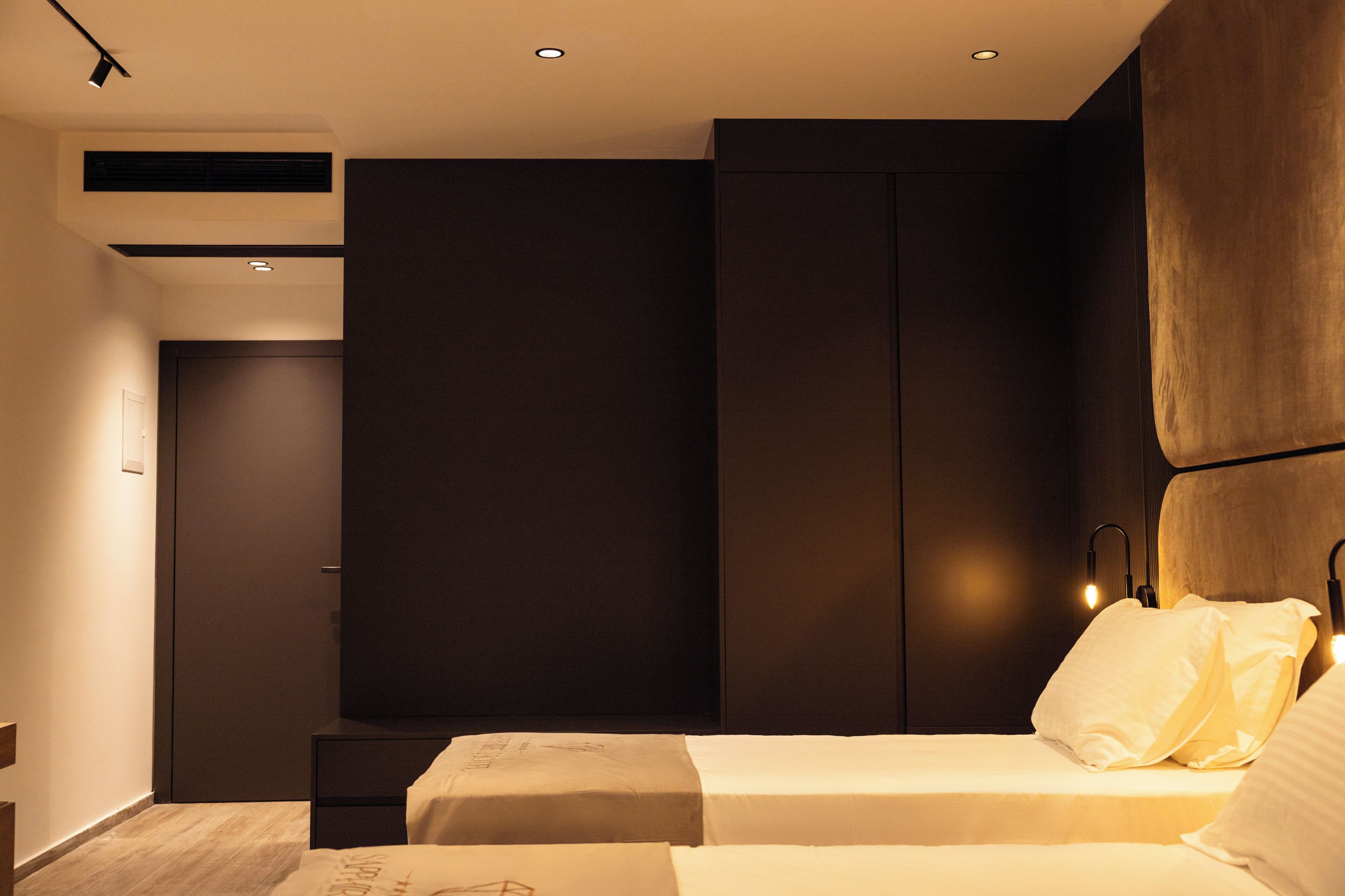 A modern bedroom with a bed, bedside tables, and built-in wardrobes.