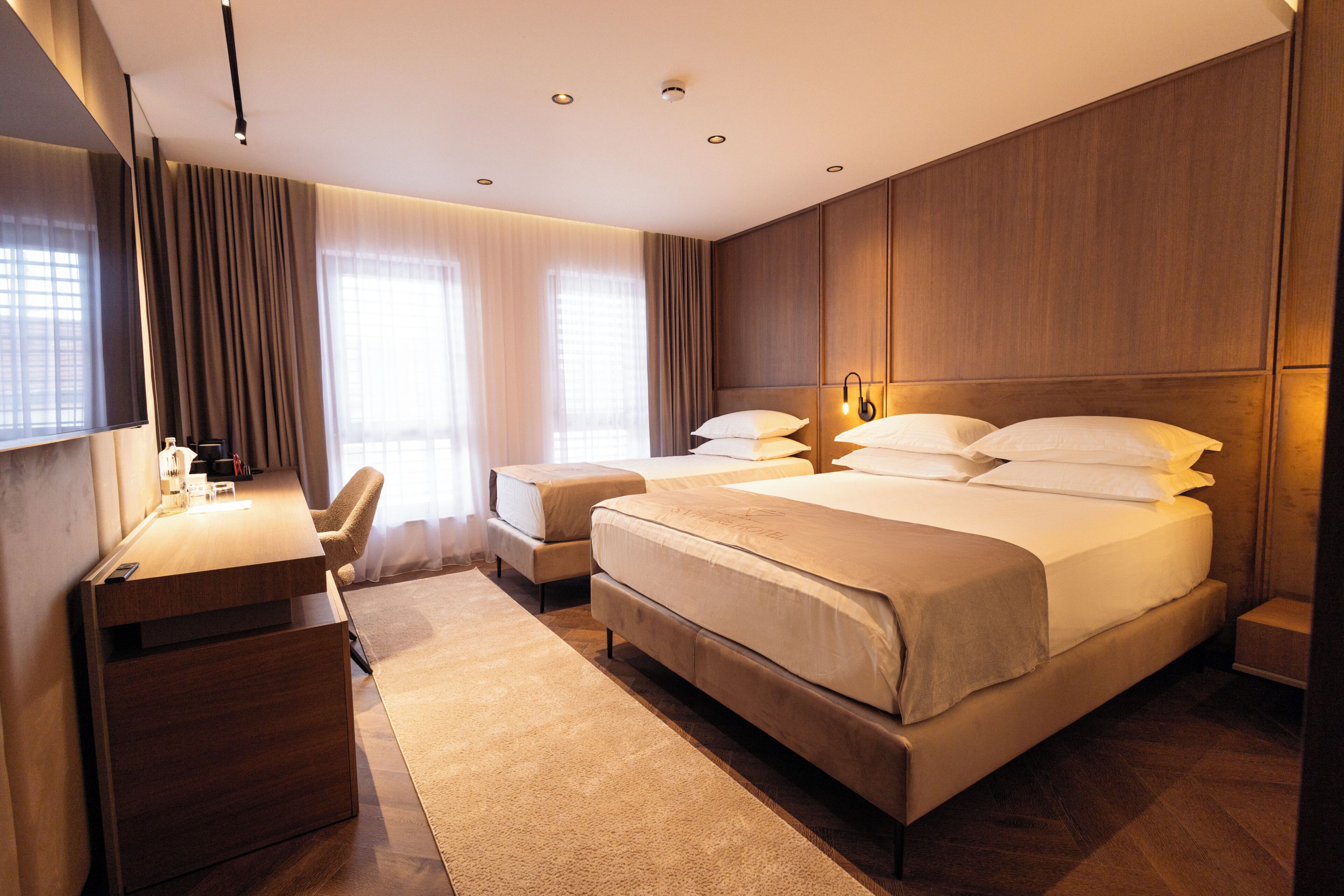 Une chambre d’hôtel moderne équipée d’un grand lit, d’un bureau, d’une chaise et d’un téléviseur à écran plat.