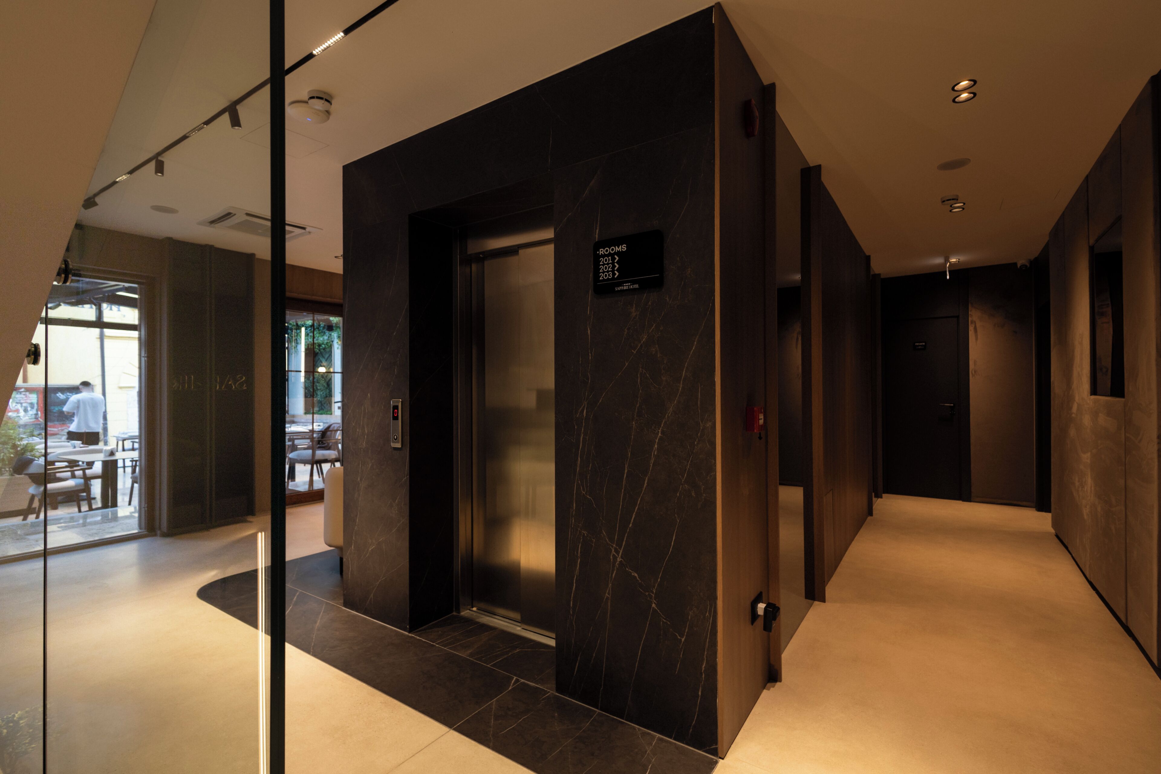 A modern elevator with a digital display, a glass partition, and a marble wall.