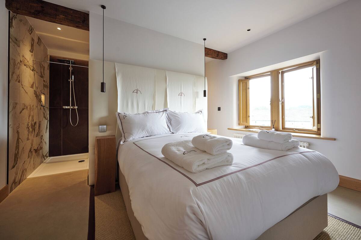 Un dormitorio con cama, toallas, ventana y zona de ducha.