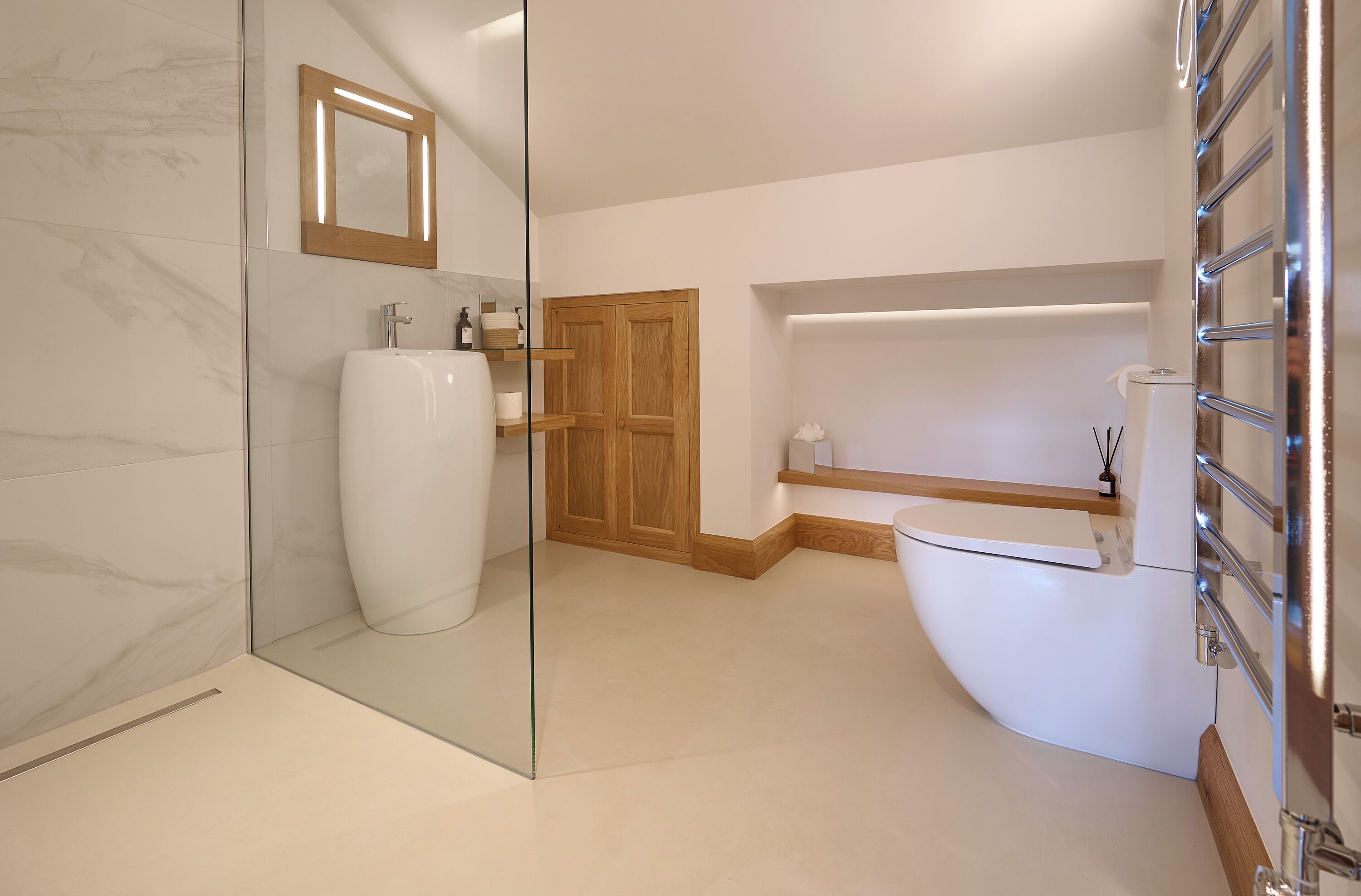 A modern bathroom with a glass shower enclosure, a white sink, wooden cabinets, and a built-in toilet.