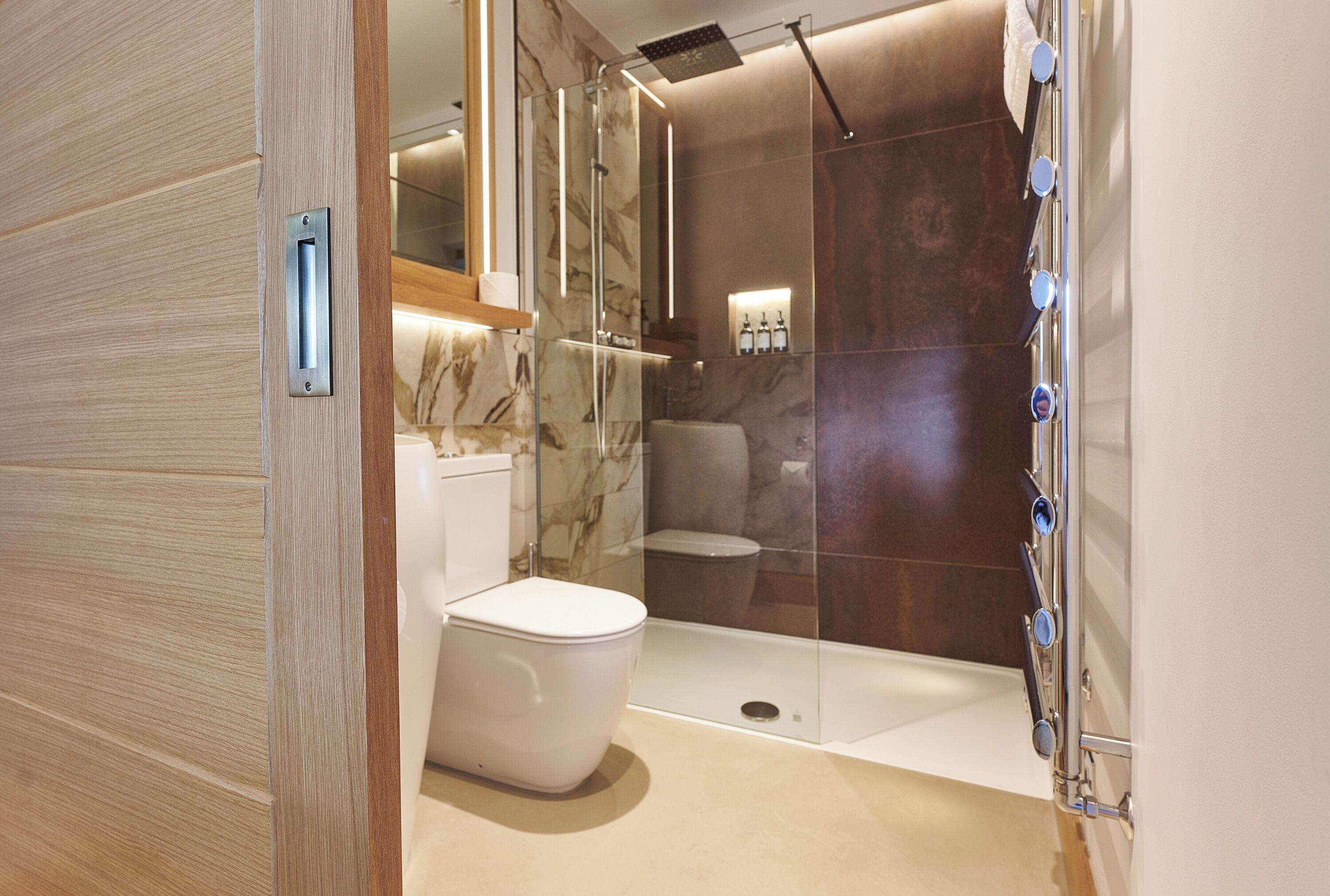 A modern bathroom with a glass-enclosed shower, a white toilet, and a marble backsplash.