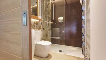 A modern bathroom with a glass-enclosed shower, a white toilet, and a marble backsplash.