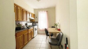 A compact kitchen with wooden cabinets, a stove, and a dining area with a table and chairs.