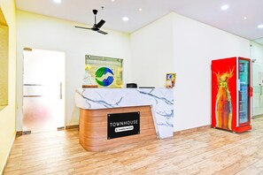 Una recepción con el rótulo 'TOWNHOUSE', encimera de mármol, ventilador de techo y máquina expendedora roja.