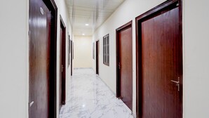 Un pasillo con puertas de madera, paredes blancas y suelo de mármol.