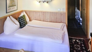Ein Doppelbett mit Holz Kopfteil, einer Wandleuchte und einem gerahmten Bild.