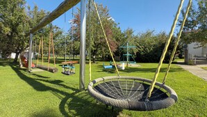 Un parque infantil con columpios, un balancín y una estructura para escalar.