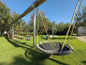 Ein Spielplatz mit Schaukeln, einer Reckschaukel und einer Kletterkonstruktion.