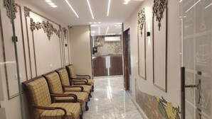 A reception area with a marble floor, wooden chairs, and decorative wall panels.