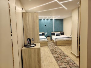 Une chambre d’hôtel moderne avec deux lits, un petit bureau doté d’une machine à café et un tapis à motifs.