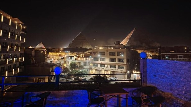 A rooftop terrace with a view of buildings and a cityscape at night.