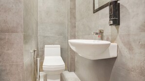 A bathroom with a toilet, a sink, and a shower. - Saver Single Royal Inn (New Delhi)