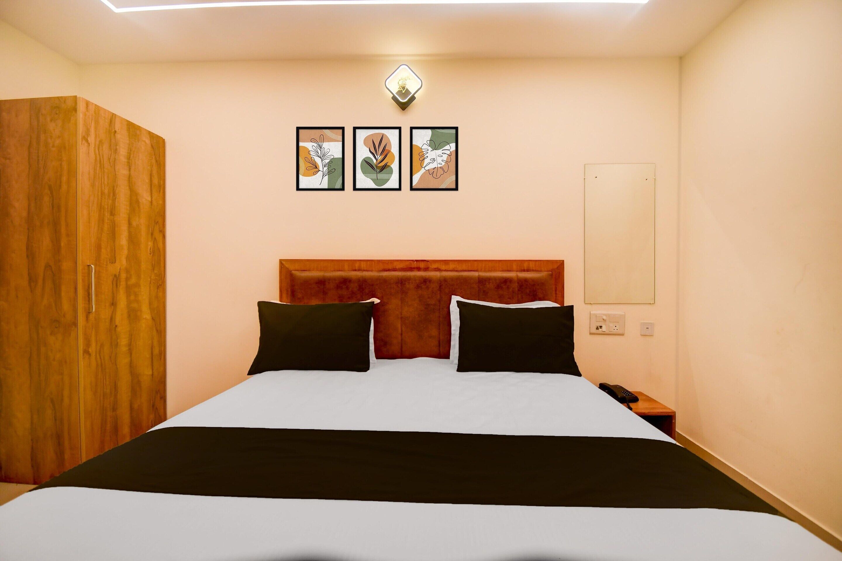 Quarto de hotel com cama, guarda-roupa de madeira e três obras de arte emolduradas na parede.