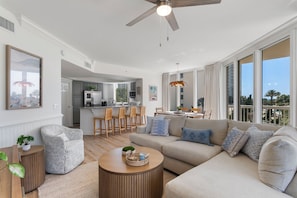 A spacious living room with a large sofa, a coffee table, and a dining area with chairs. - Spacious 3 bed 3 bath @ Silver Shells in Destin - Sleeps 8 (Destin)
