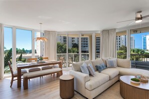 A spacious living area with a large window, a sofa, a dining table, and a ceiling fan. - Spacious 3 bed 3 bath @ Silver Shells in Destin - Sleeps 8 (Destin)