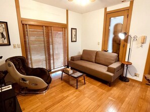Una sala de estar con un sillón de masajes, un sofá, una mesa de centro y una lámpara.