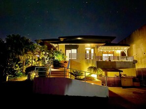Una casa moderna con un porche cubierto, una escalera y una entrada bien iluminada.