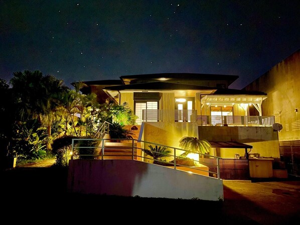 A modern house with a covered porch, a staircase, and a well-lit entrance.